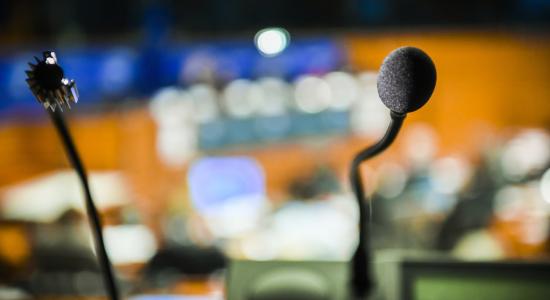 Blurred conference room in background with two microphones in focus